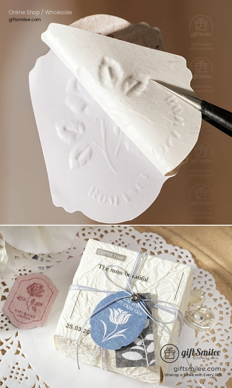 White embossed paper with floral design paired with a gift box wrapped in textured ivory paper and blue floral tag