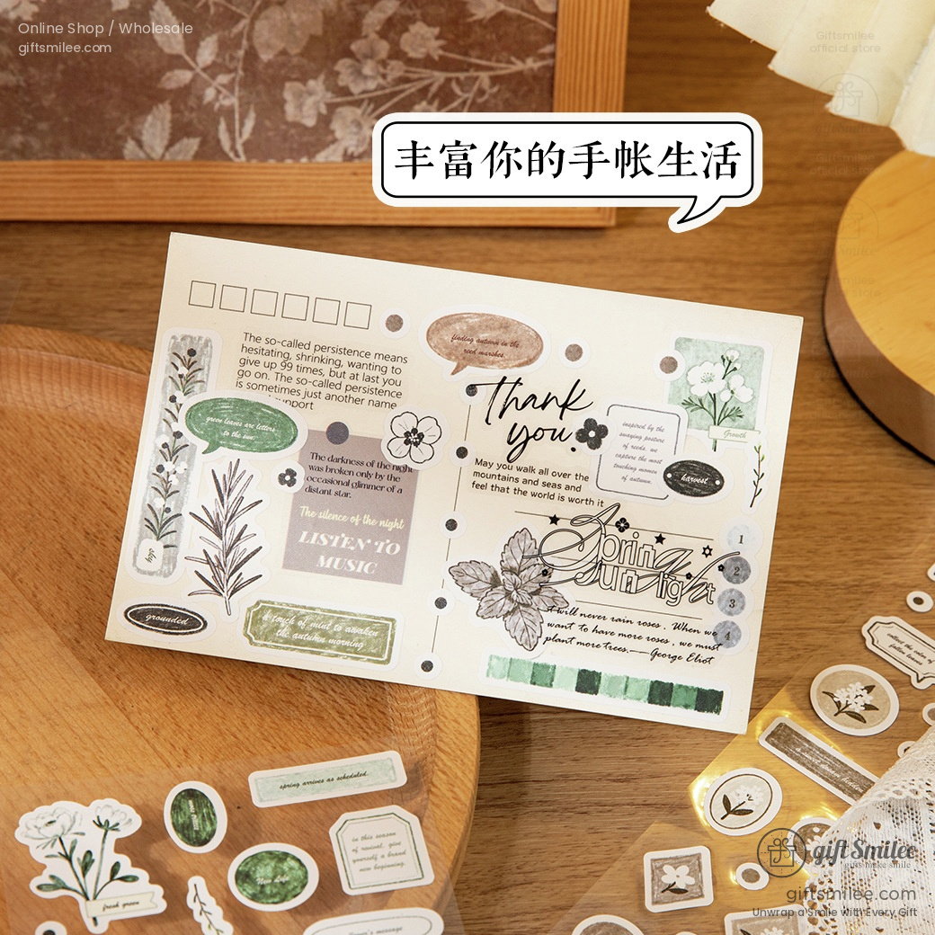 Vintagestyle journal stickers with floral designs text quotes and green accents on a wooden tabletop
