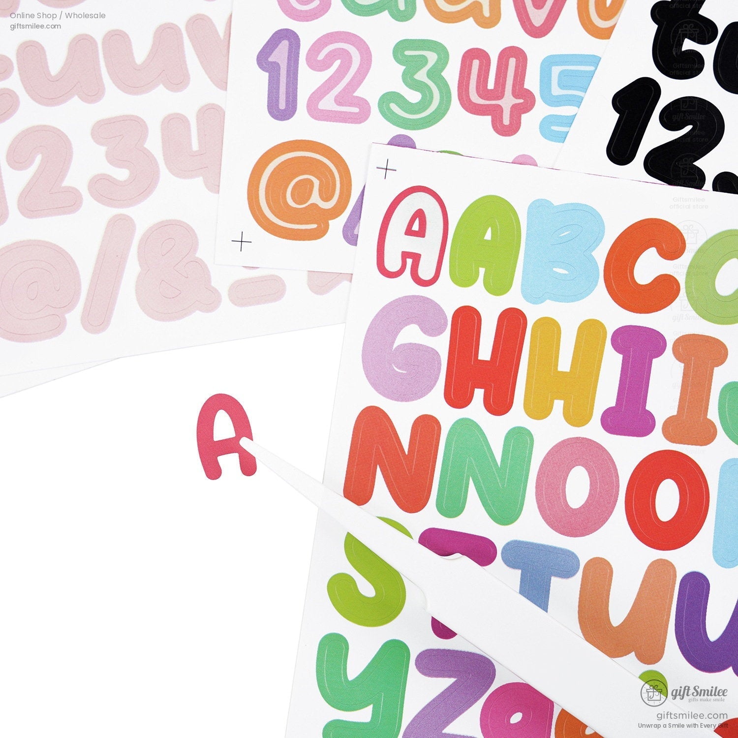 Assorted colorful alphabet and number sticker sheets with bold rounded letters and a precision tool lifting a red A