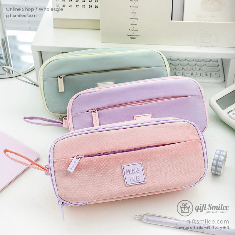 Three pastel pencil cases in green, purple, and pink, arranged neatly on a desk