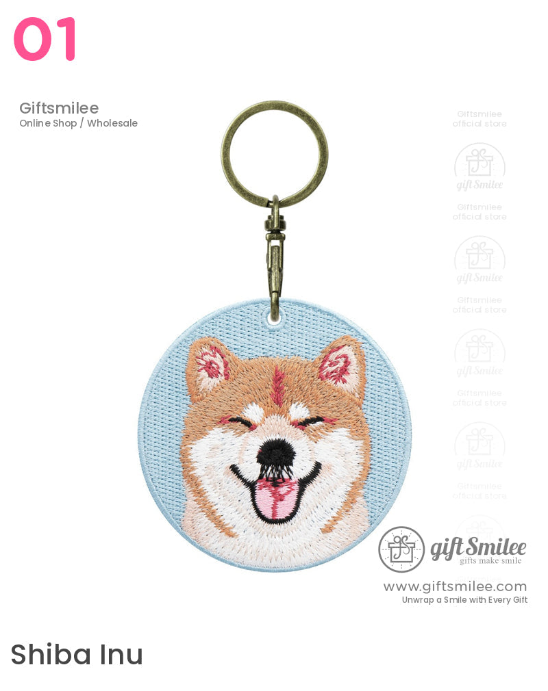 Light blue embroidered keychain featuring a smiling Shiba Inu face in tan white and pink hues with a bronze clasp