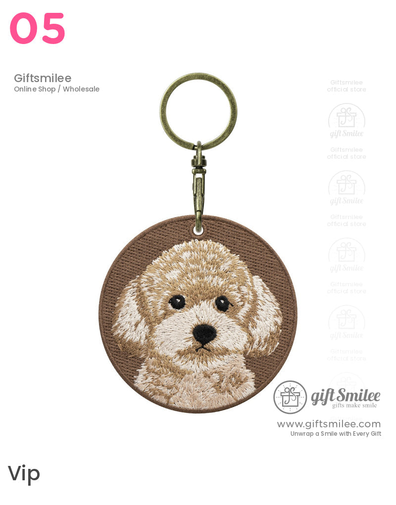 Brown circular keychain with embroidered beige poodle face bronze metal clasp and textured fabric backdrop