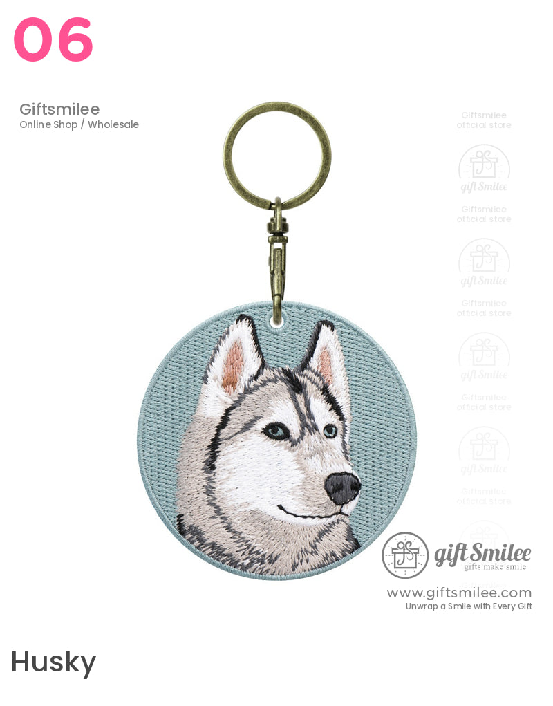 Circular keychain with embroidered husky face on a light blue fabric background and antique brass key ring