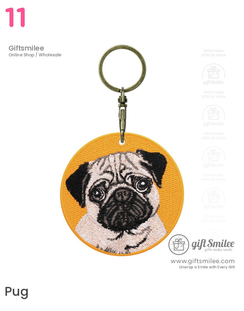 Round orange fabric keychain featuring an embroidered pug face with black and beige details antique brass clasp