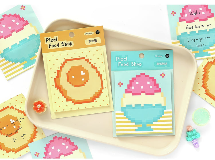 Pixel art sticky notes with fried egg and ice cream designs pastel colors on a beige tray surrounded by matching cards